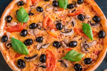 Tasty fresh hot pizza against a dark background. Pizza, food, vegetable, mushrooms.  It can be used as a background