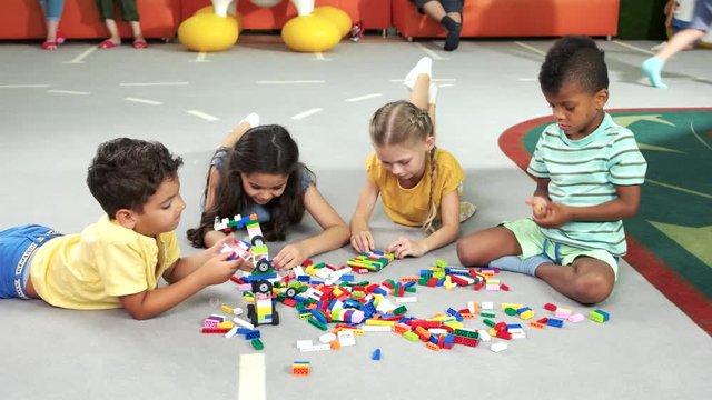 Group of kids playing with block toys. Children playing together with colorful plastic toy constructor in playroom. Spend time with pleasure.