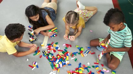 Preschool kids playing with toys on the floor. Children playing constructor, top view. Kids development center.