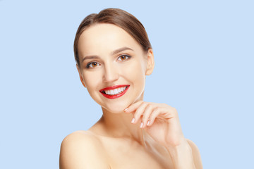 Obraz na płótnie Canvas Teeth and skin care. Beautiful young woman with fresh skin and red lips looking straight and demonstraiting healthy teeth.