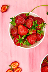 Ripe red strawberries on pink table, Strawberries in white bowls. Fresh strawberries. Beautiful strawberries. Diet food. Healthy, vegan. Top view. Flat lay.