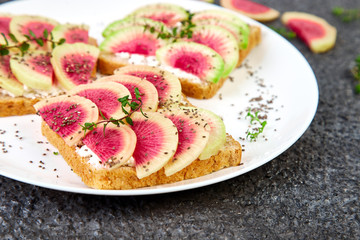 Healthy breakfast toasts from sliced watermelon radish or chinese daikon, chia and cottage cheese on black background. Copy space.
