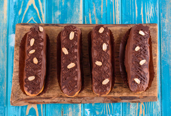 Delicious chocolate and peanut eclairs on a blue wooden table