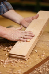 The carpenter touches and strokes the wooden part.