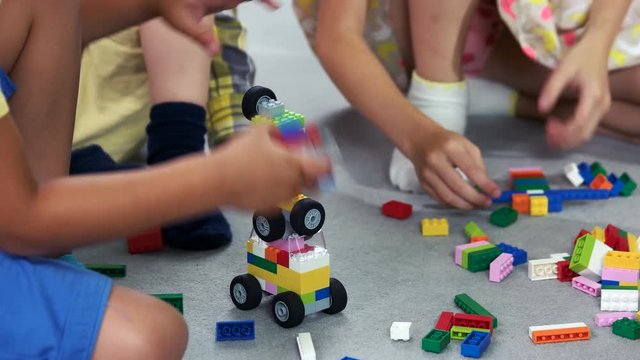 Close up kids playing with block toys in nursery school. Children playing with colorful constructor in play school. Benefits of playing with building blocks.