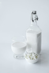 Bottle of milk, cottage cheese in white bowl  at white background