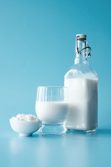 Glass of milk and cottage cheese at blue background