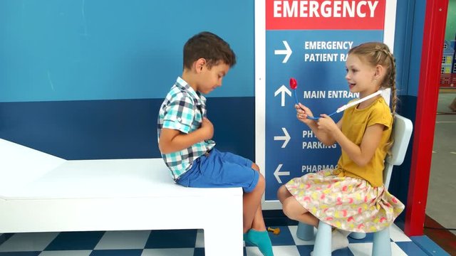Two children playing doctor in playroom. Little girl doctor examining boy patient with toy stethoscope. Childrens role play center.