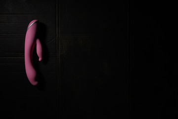 purple dildo on dirty dark background with hard light and shadows with copyspace.