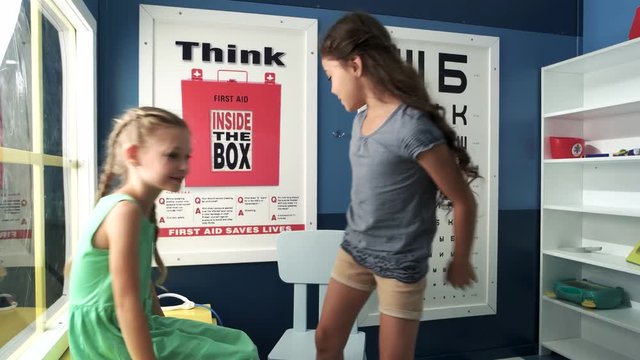 Little girls playing doctor and patient. Cute girl playing ear nose throat specialist examining young girl at doctors office.