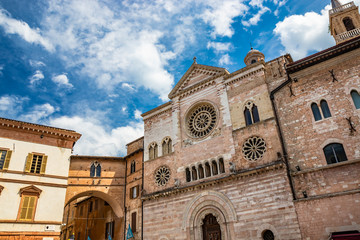 The Cathedral of San Feliciano in the square of Foligno. The side facade, with 3 rosettes, mullioned windows, arches and columns. The bell tower, the dome and the wooden portal. Perugia, Umbria, Italy