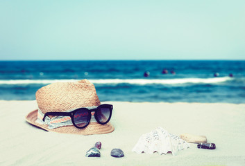 Fototapeta na wymiar Vintage wicker straw hat and black sun glasses on a tropical beach, summer concept .