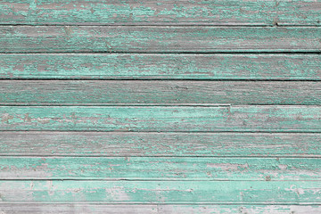 Old wooden wall of the house covered with cracked green paint