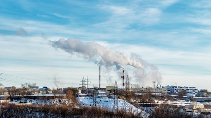 In the center of the picture Smoking pipes, high-voltage power lines, plant buildings. In the foreground is a wasteland. Winter.