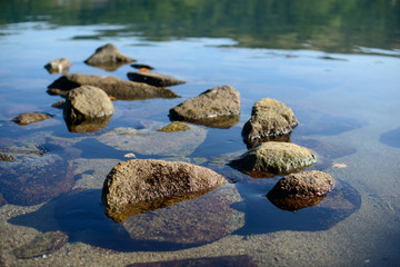Wet pebbles on seashore in evening sun light. Sea wave on seacoast with round stones.