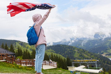 Full length profile shot of beautiful young woman with American flag held in her outstretched hand...