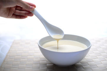 Hand holding a spoon dipping into a soup