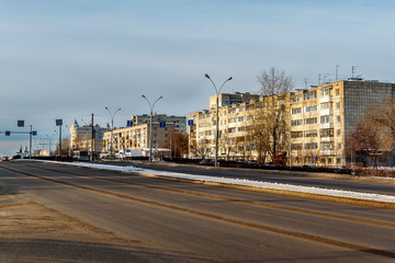 Obraz premium Before us is part of the street of the Stakhanov city of Perm. Wide clean roads, a little snow on the roadside, illuminated by the sun at home.