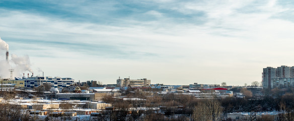 Fototapeta premium Outskirts Of Perm. In the foreground trees and a variety of low buildings. In the distance you can see Smoking chimneys, industrial buildings. On the right we see houses.