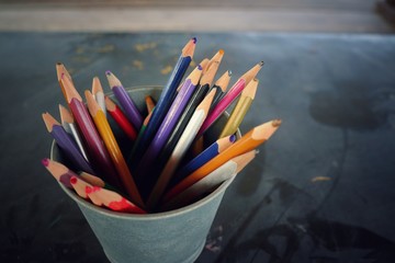 Soft focus of used color pencils in metal pot on the table. Vintage style picture. Object and...