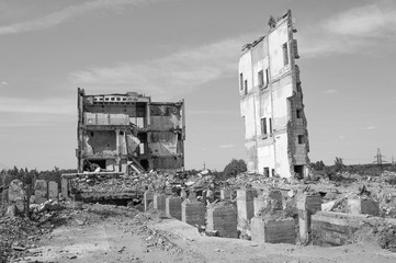Remains of a large building with concrete Foundation piles in the foreground. Background. Black and white