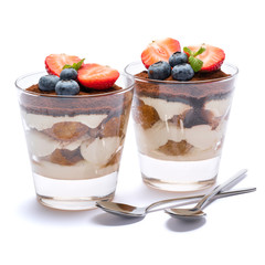 Classic tiramisu dessert with blueberries and strawberries in a glass isolated on a white background with clipping path