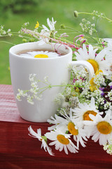 A cup of tea with daisies bouquet	