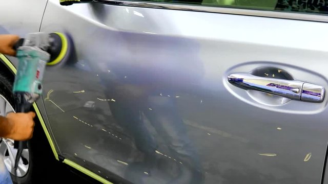 Worker buffer car with polish wax using grinder machine at car salon