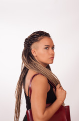 Fototapeta premium Portrait of a European girl with African pigtails, shaved temples and a dark red bag on a white background