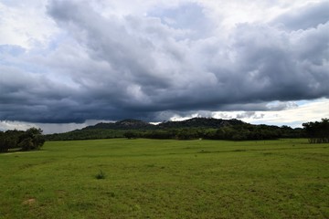 Fototapeta na wymiar Grey skies over African savannah and hills landscape