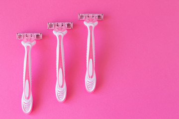 Three women's razors pink color on an a pink background. Razor for personal hygiene for hair removal