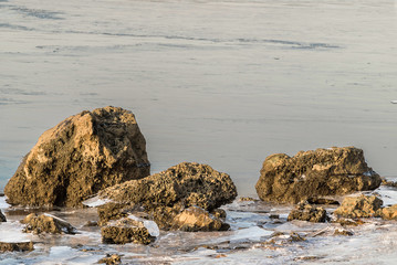 Coastal rocks, chunks of ice and freezing water of the river.