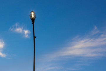 city street lantern illumination in evening twilight time photography from below on blue sky background, infrastructure and landscaping concept picture with empty space for copy or text
