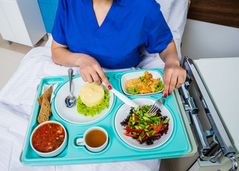 Tray with breakfast for the young female patient. The young woman eating in the hospital.