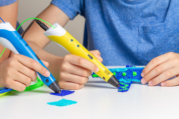 Two kid hands creating with 3d printing pens