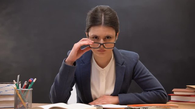 Angry teacher looking aggressively to camera taking off glasses, strict lecturer