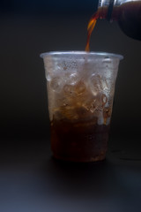 Pouring coffee into a glass with ice cube