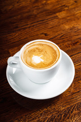 cup of cappuccino on the wooden background