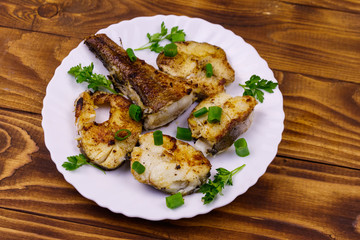 Roasted pollock in white plate on a wooden table