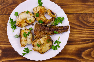 Roasted pollock in white plate on a wooden table