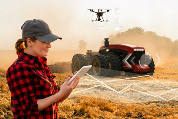 Woman farmer with digital tablet controls an autonomous tractor and drone on a smart farm	