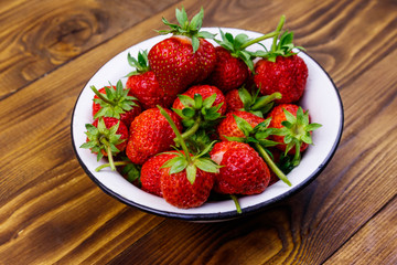 Fresh ripe strawberry in white bowl on a wooden table