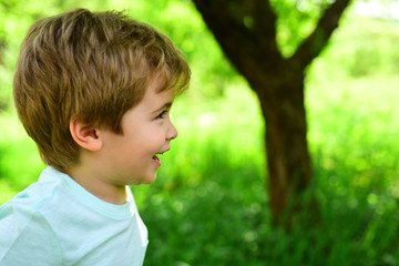 Happy smile, funny child, cute boy kid. Portrait of a beautiful happy little boy close-up. Funny smiling little children showing teeth on green nature background. A walk in the park with a child