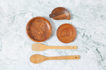 Flat lay top view of wooden spoons, wooden disk pattern on marble table.