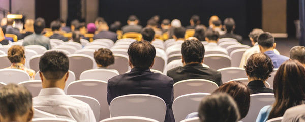 Banner cover page of Rear view of Audience listening Speakers on the stage in the conference hall...