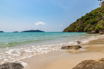 Long beach of Koh Chang island. Tropical sandy beach with palm trees and tropical forest. Thailand.
