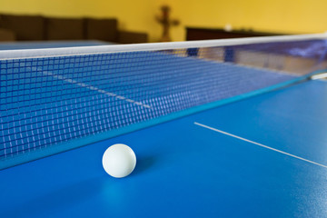 A tennis white ball for Ping-Pong on a blue table. A Ping-Pong game. Sport games.