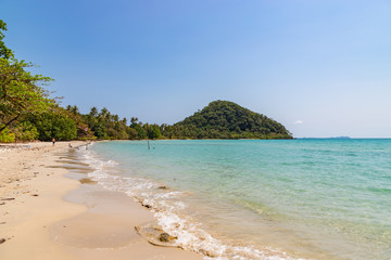 Long beach of Koh Chang island. Tropical sandy beach with palm trees and tropical forest. Thailand.