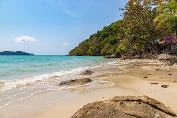 Long beach of Koh Chang island. Tropical sandy beach with palm trees and tropical forest. Thailand.