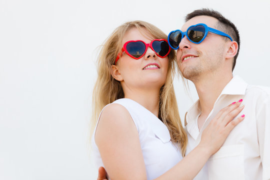 Man and woman wearing heart shape sunglasses